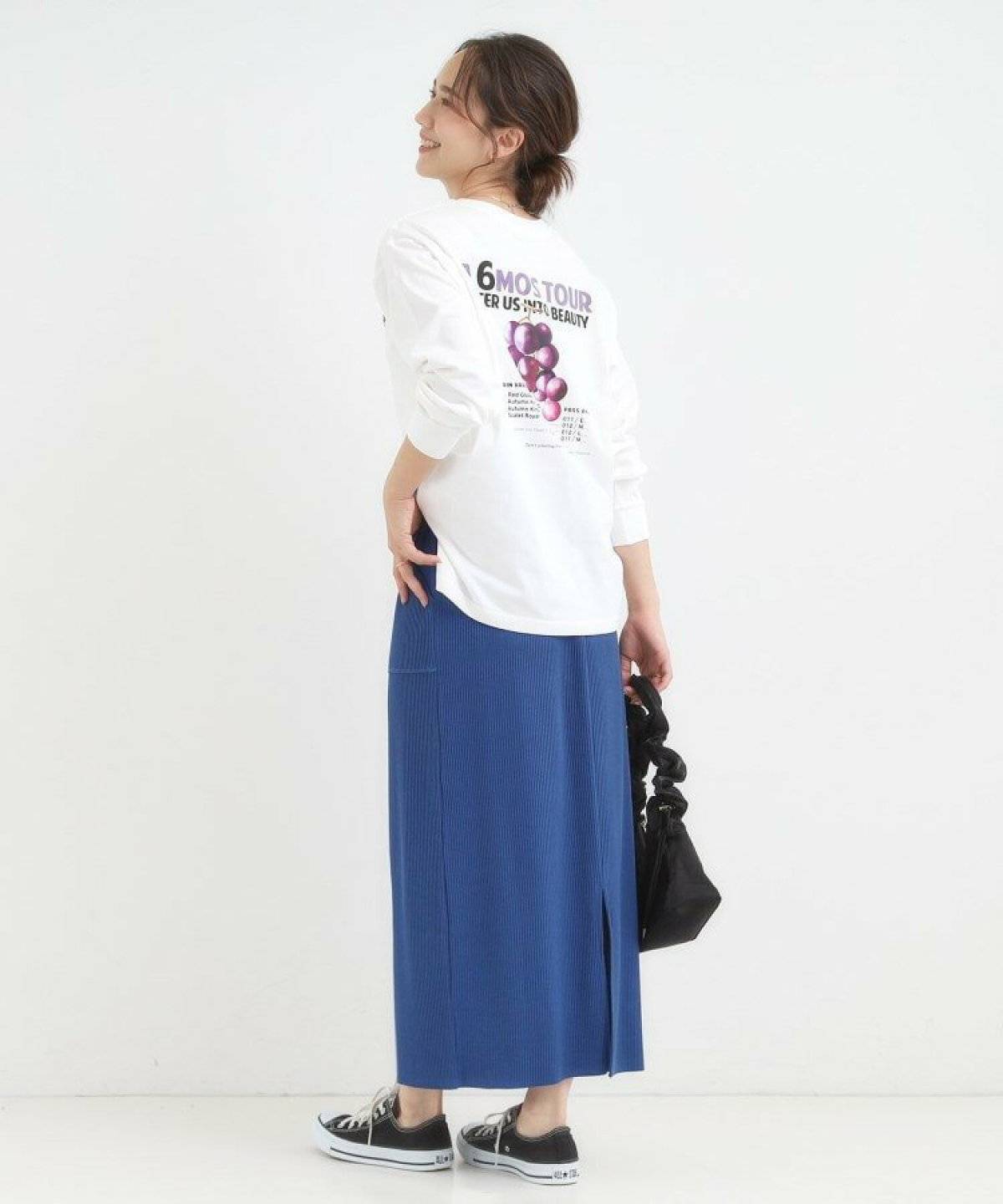 ロゴTシャツにブルーのスカートを合わせた女性