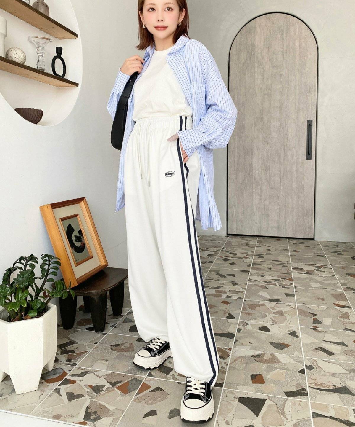 ストライプ柄のブラウスにジャージパンツを合わせた女性