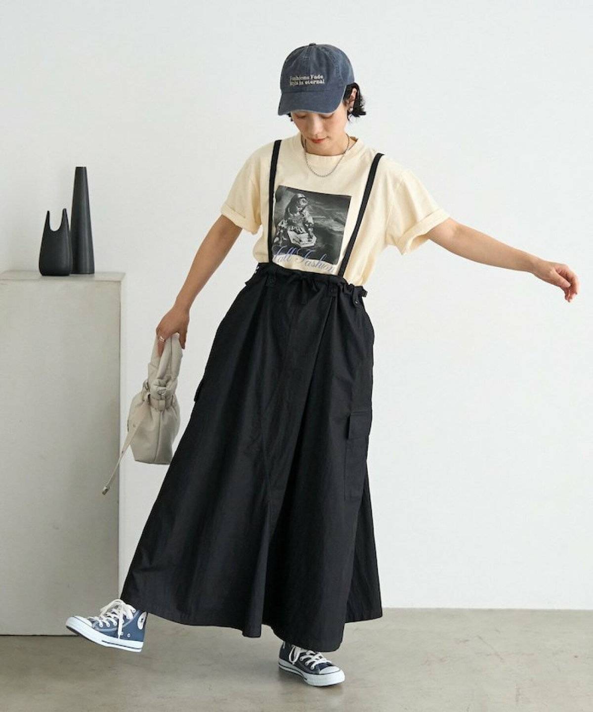 ベージュのTシャツに黒のキャミワンピースを重ねた女性