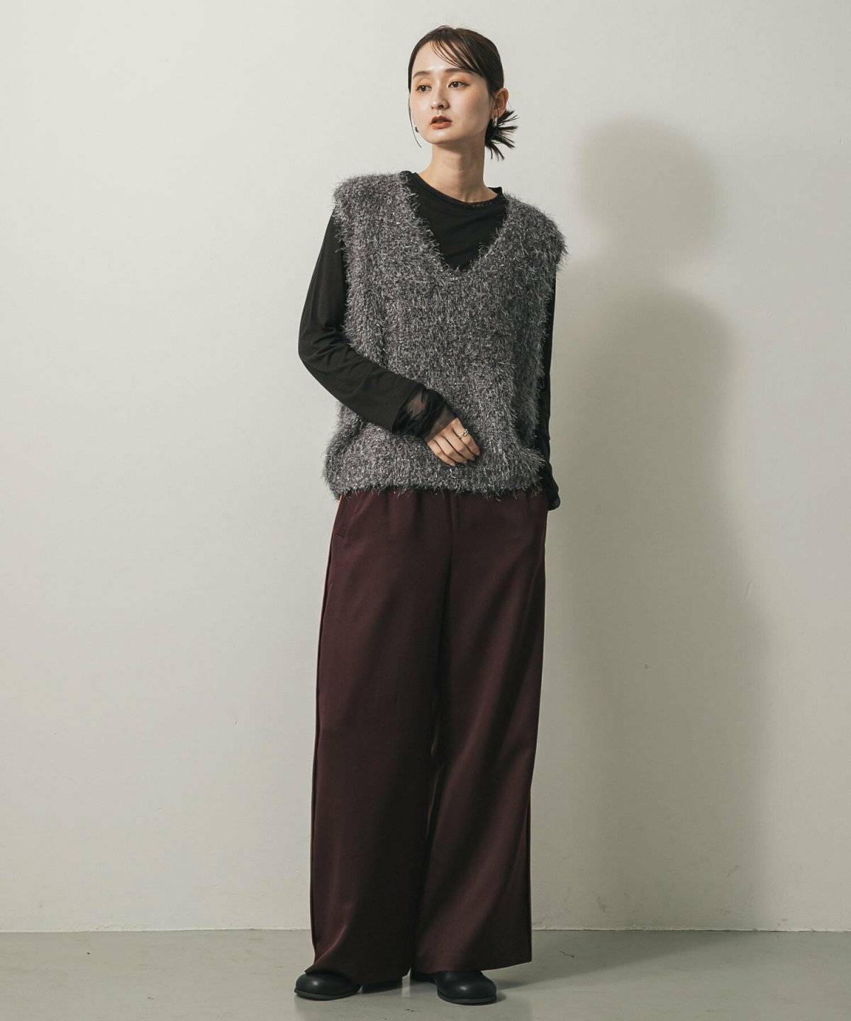 トップスにベストを重ねてパンツを合わせた女性