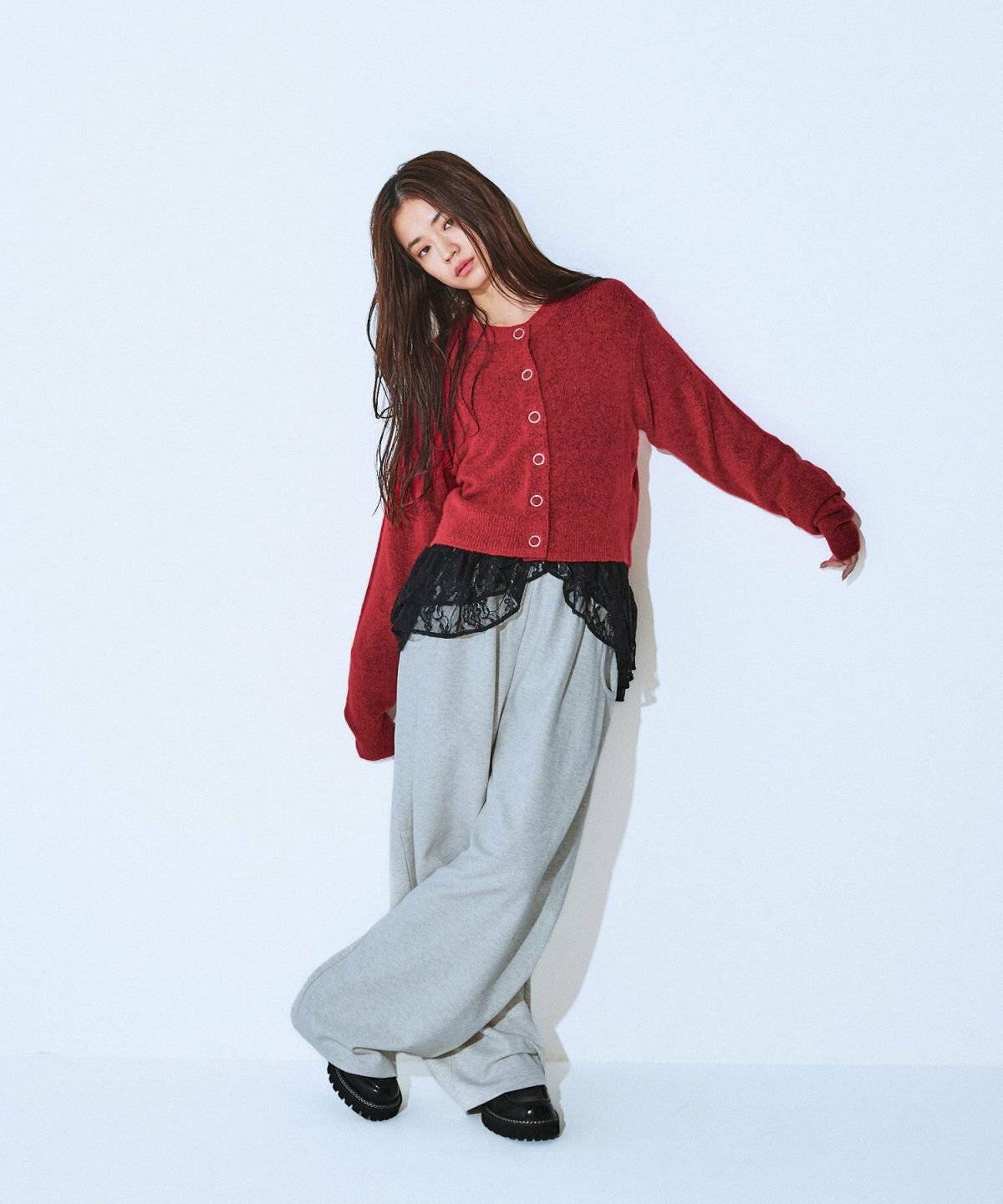 赤のカーディガンにグレーのスウェットパンツを合わせた女性