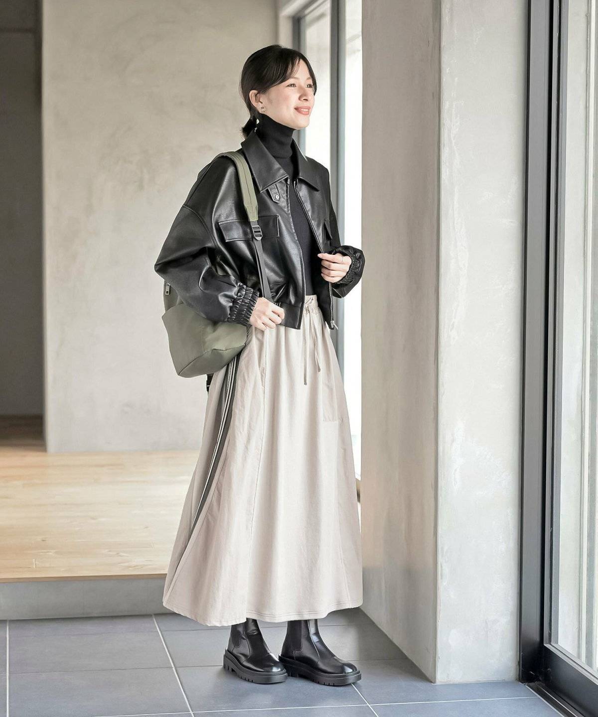 黒アウターにベージュのスカートを合わせた女性