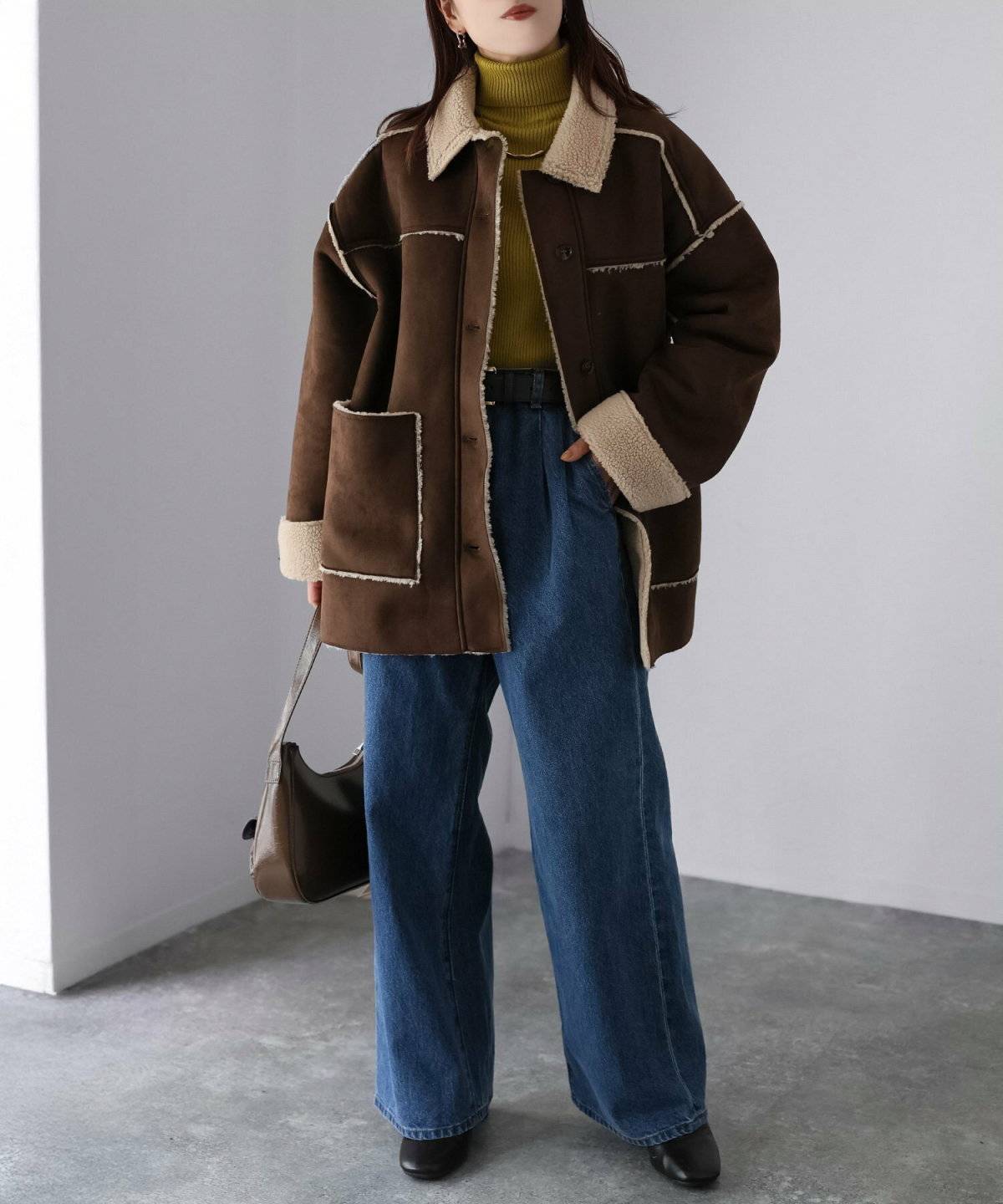 ニットにムートンジャケットを羽織ってデニムを合わせた女性