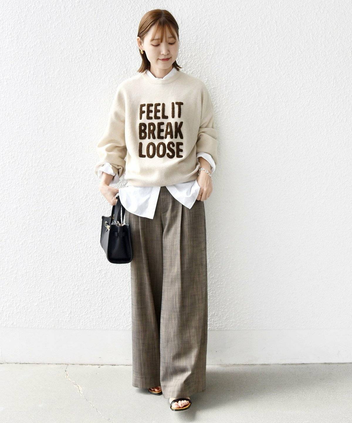 ベージュのニットにブラウンのパンツを合わせた女性