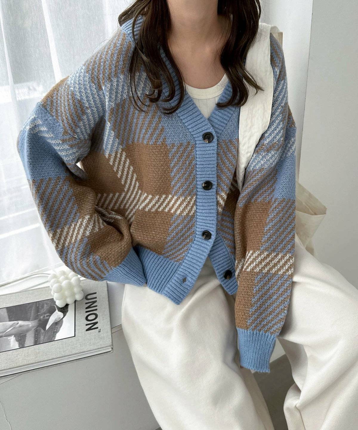 チェック柄カーディガンに白パンツを合わせた女性