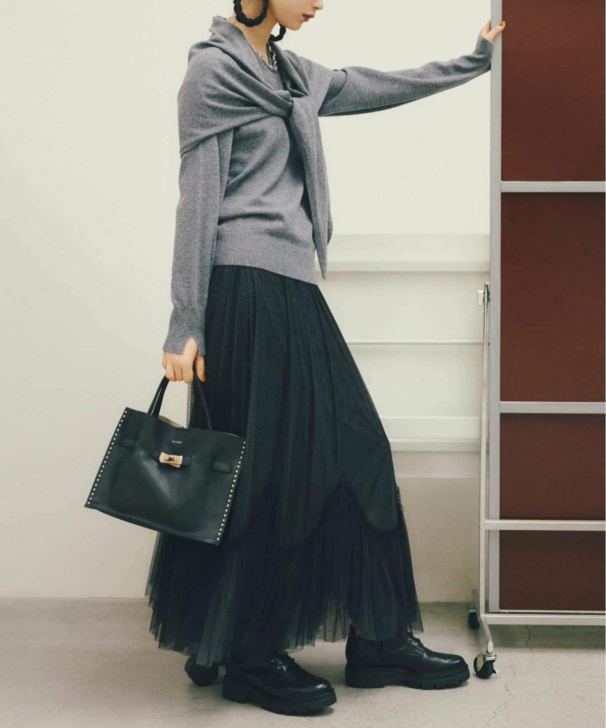 グレーのニットに黒スカートを合わせた女性
