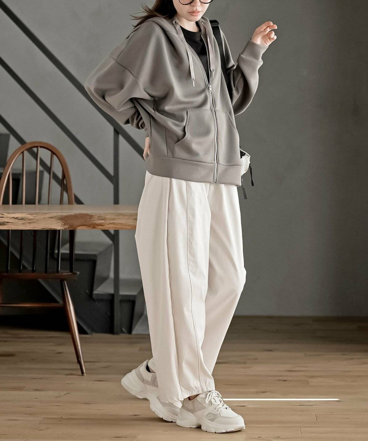 ブラウンパーカーに白パンツを合わせた女性