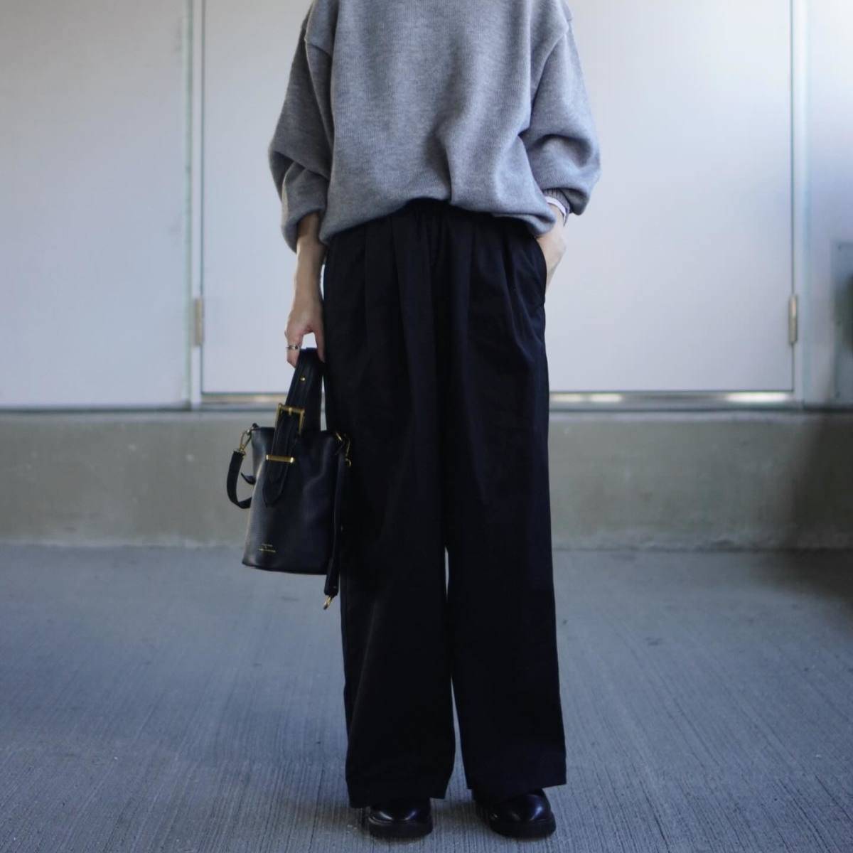 グレーニットに黒パンツを合わせた女性