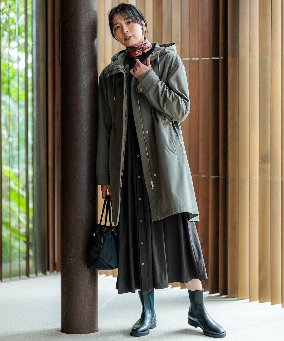 グリーンのダウンに黒ワンピースを合わせた女性