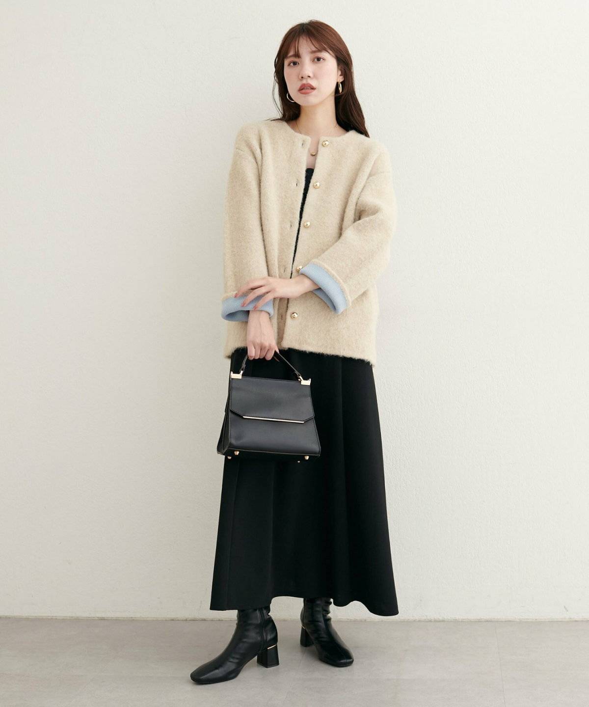 ブラックコーデにベージュのカーディガンを羽織った女性