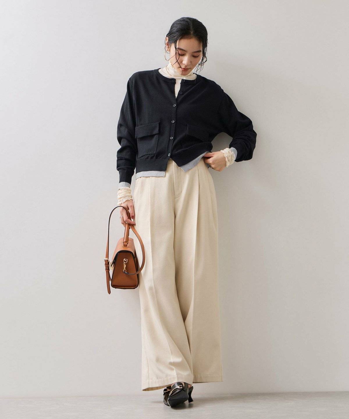 ベージュコーデに黒カーディガンを羽織った女性