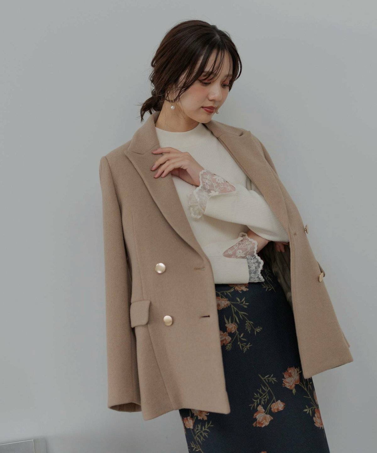 ホワイトコーデにベージュのジャケットを羽織った女性