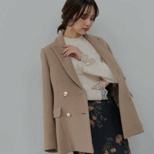  ホワイトコーデにベージュのジャケットを羽織った女性 