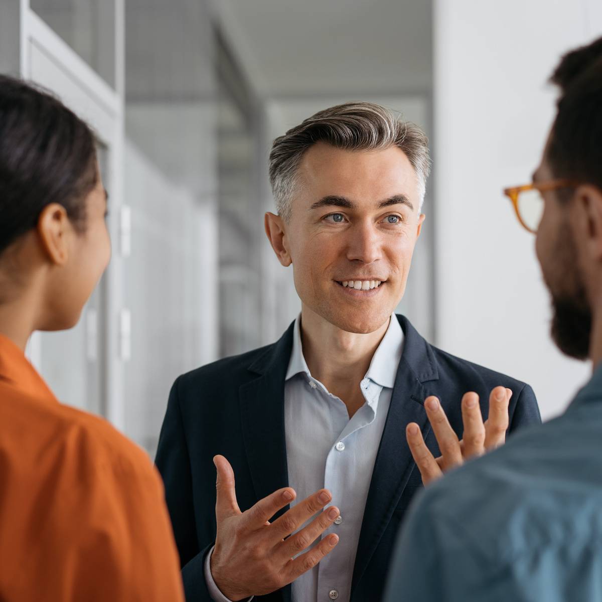 立ちながら同僚と話す男性