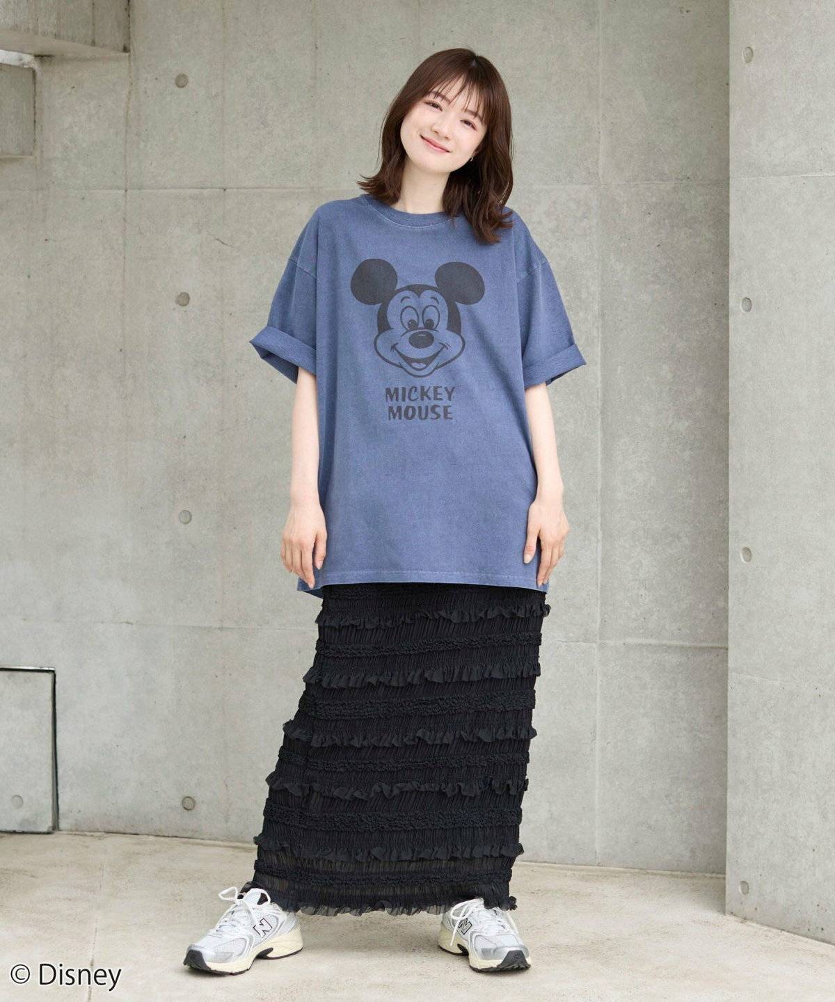 ネイビーのTシャツにブラックスカートを合わせた女性