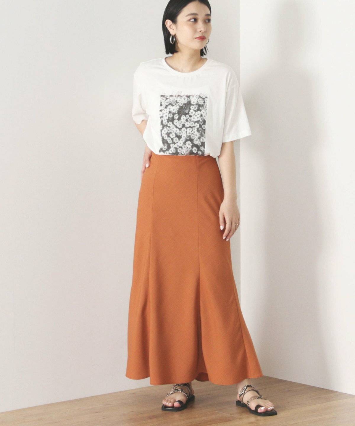 ベージュのTシャツにオレンジのスカートを合わせた女性