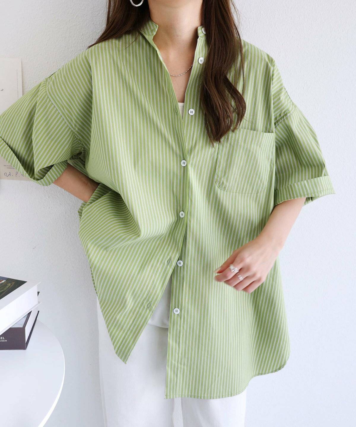 グリーンのシャツにホワイトのパンツを合わせた女性