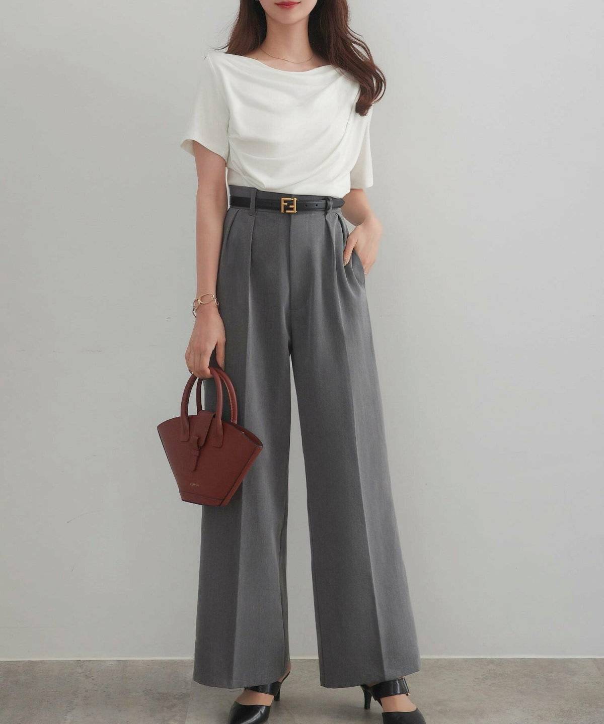 ホワイトのトップスにグレーのパンツを合わせた女性