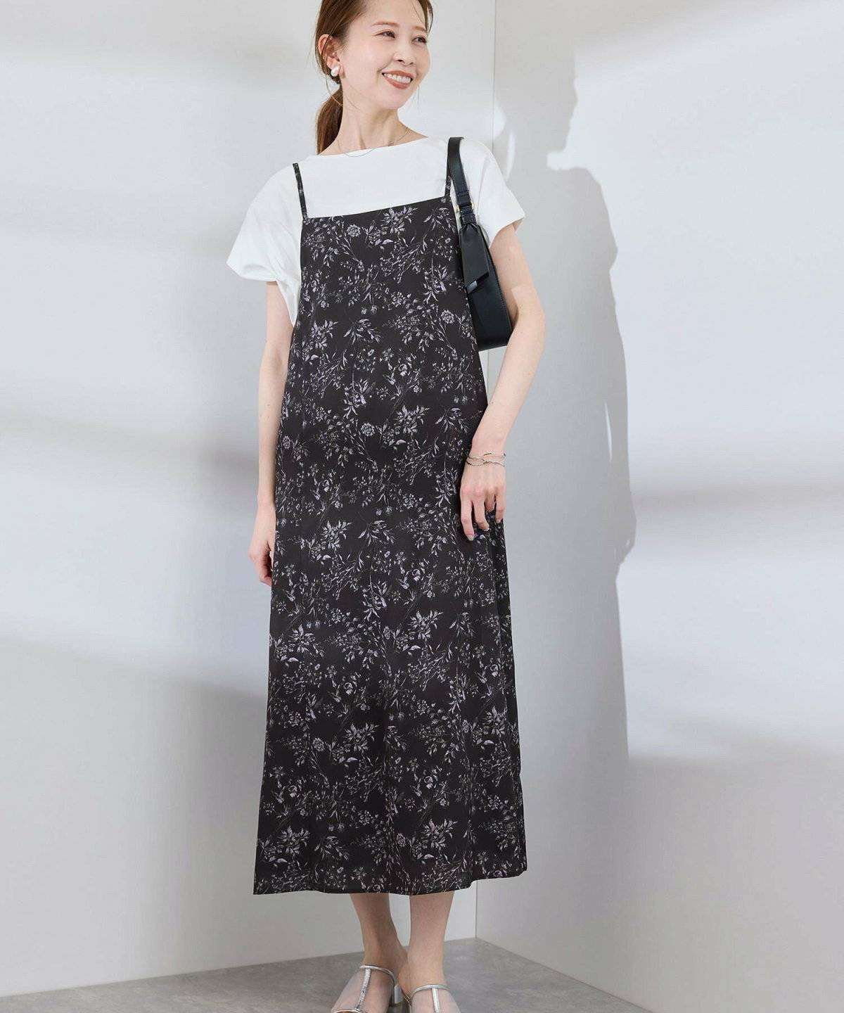 ホワイトのブラウスに花柄キャミワンピースを合わせた女性