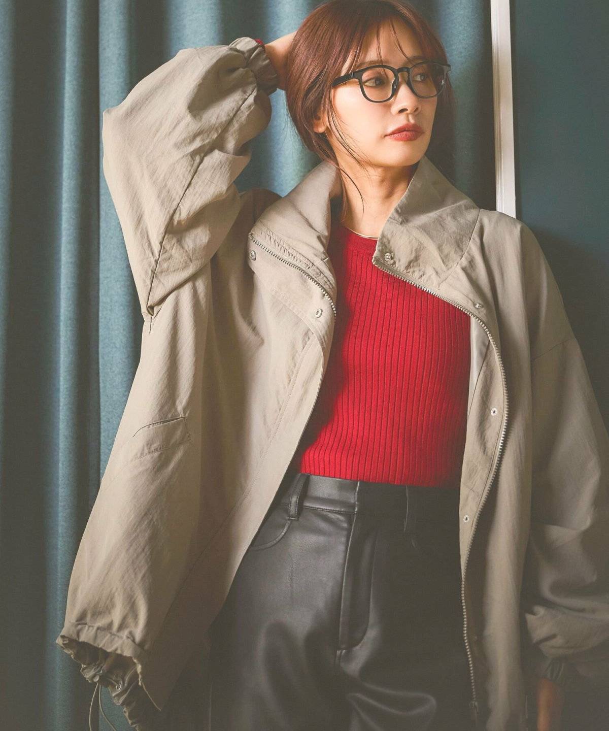 赤のニットにパンツを合わせてグリーンのブルゾンを羽織った女性