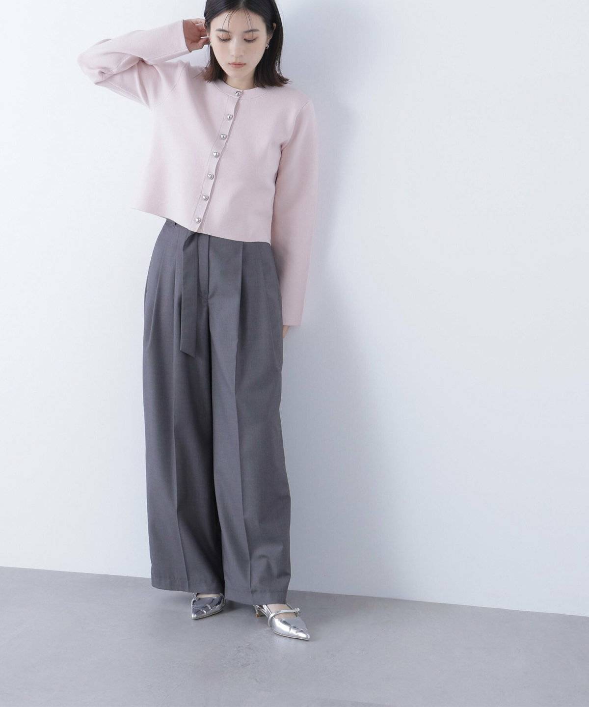 ピンクのトップスにグレーのパンツを合わせた女性