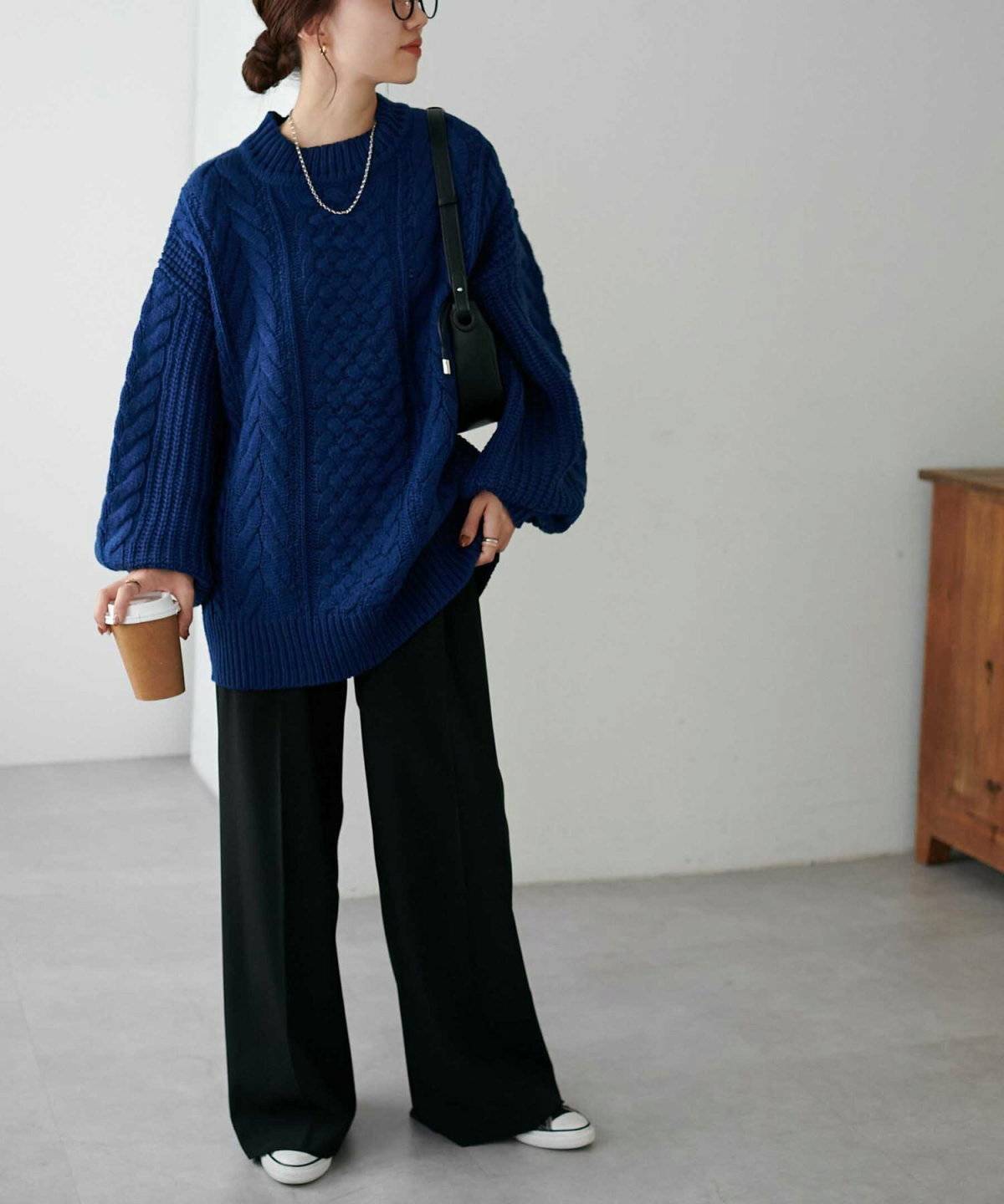 ブルーのニットに黒パンツを合わせた女性