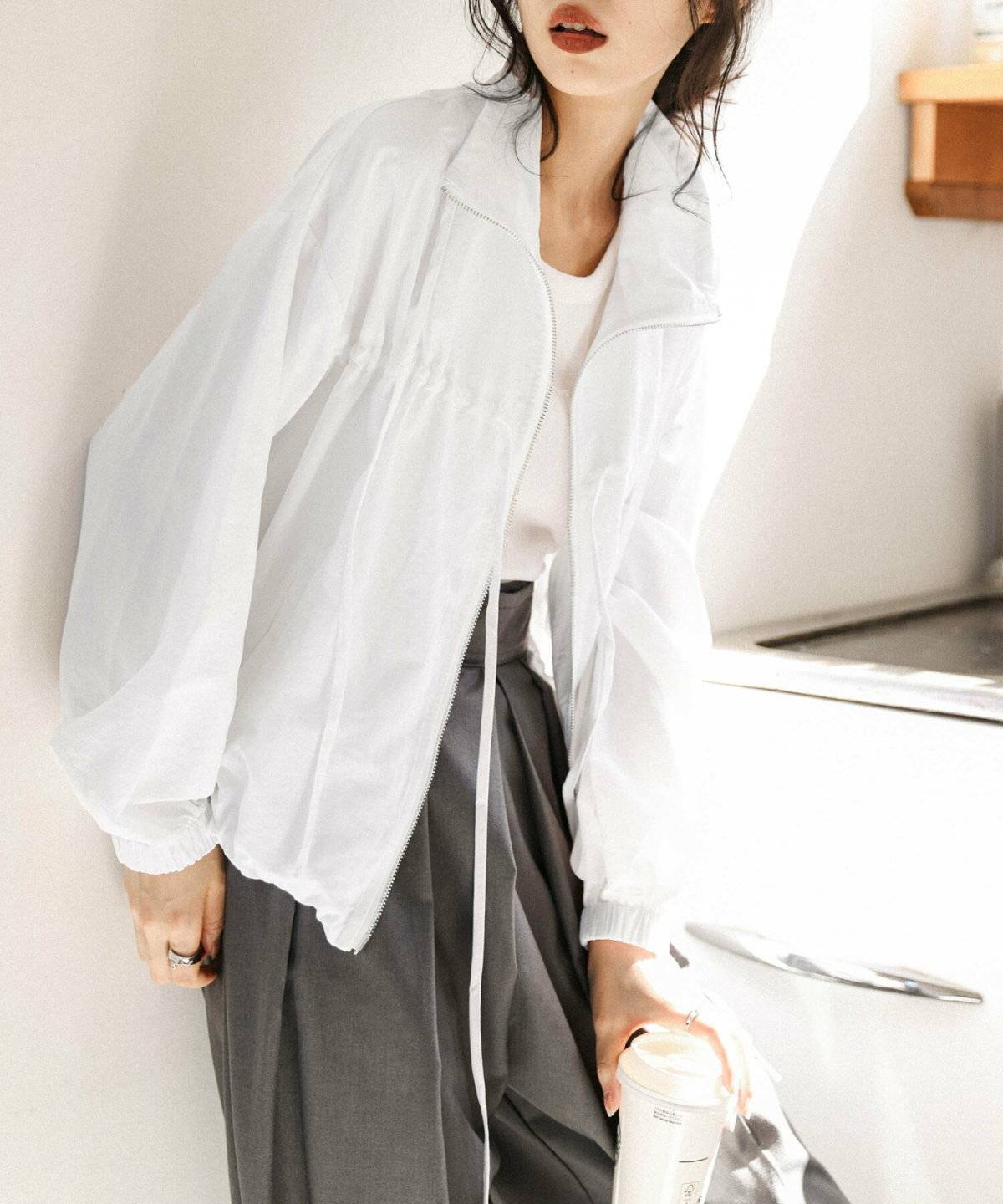 白トップスにグレーのパンツを合わせた女性