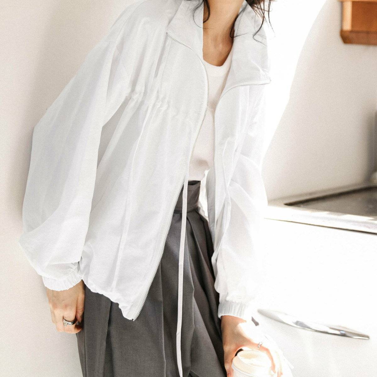 白トップスにグレーのパンツを合わせた女性