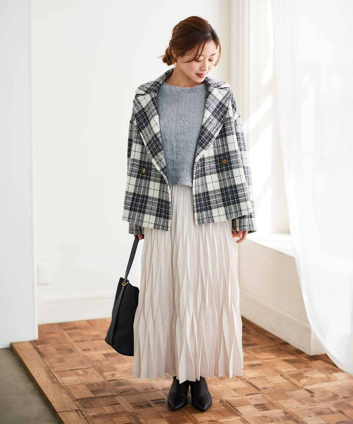 モノトーンコーデにブラウンのチェック柄アウターを羽織った女性