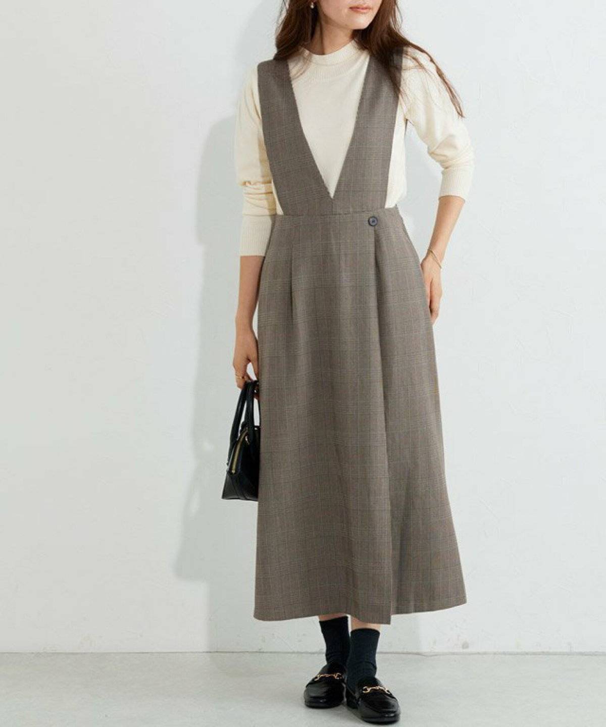 白ニットにチェック柄ワンピースを重ねた女性