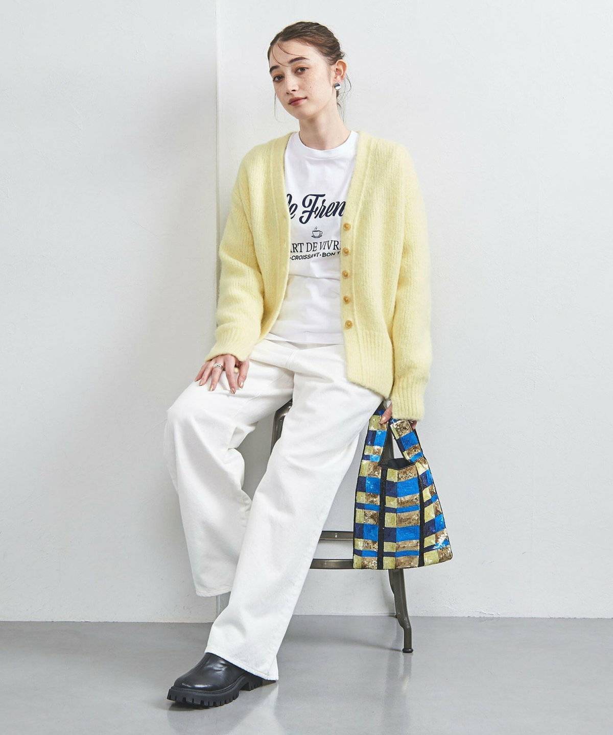 イエローのカーディガンに白パンツを合わせた女性