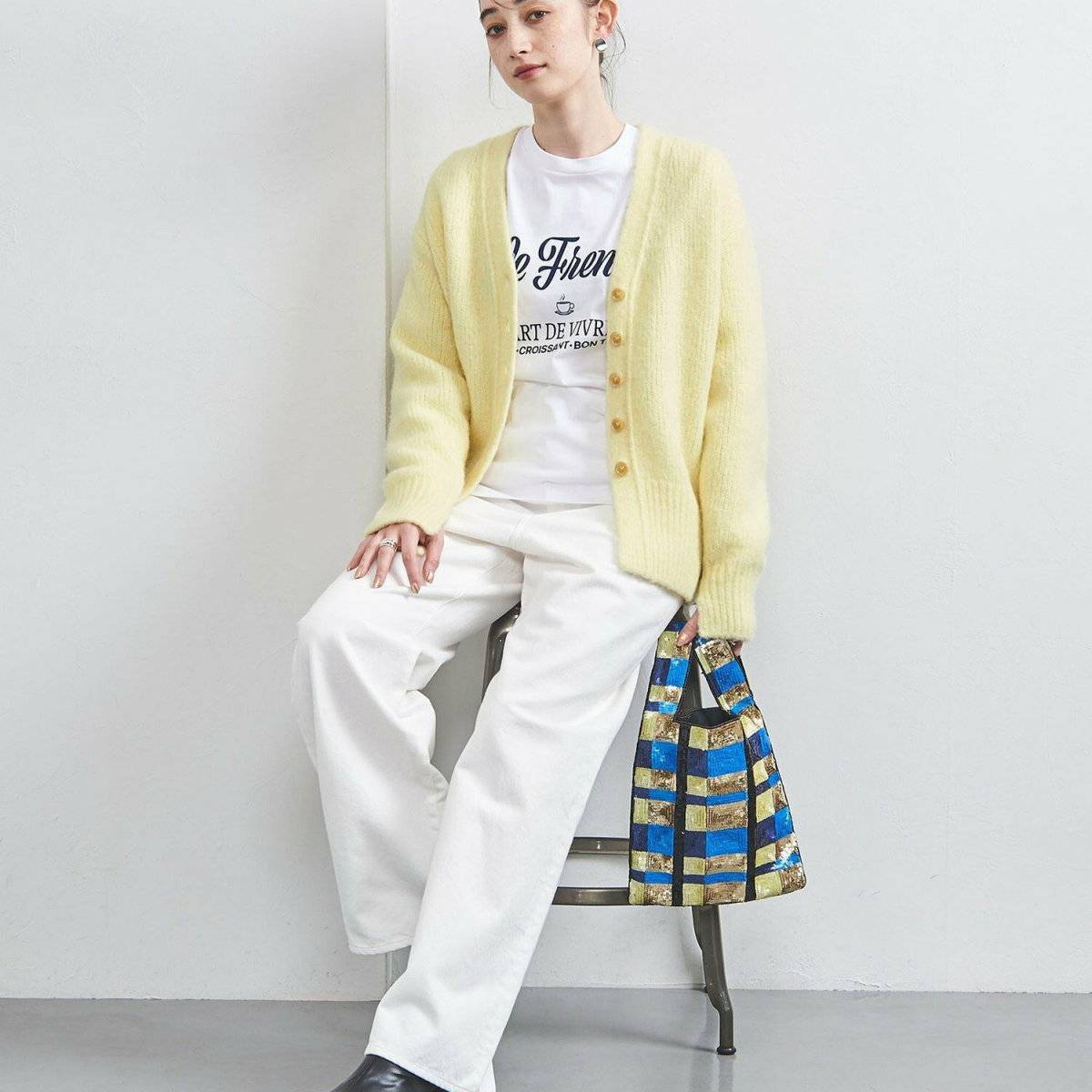 イエローのカーディガンに白パンツを合わせた女性