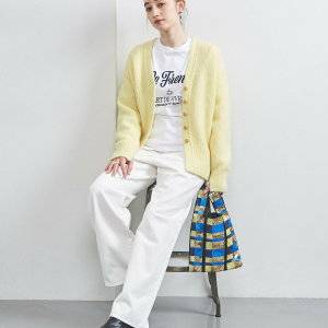  イエローのカーディガンに白パンツを合わせた女性 