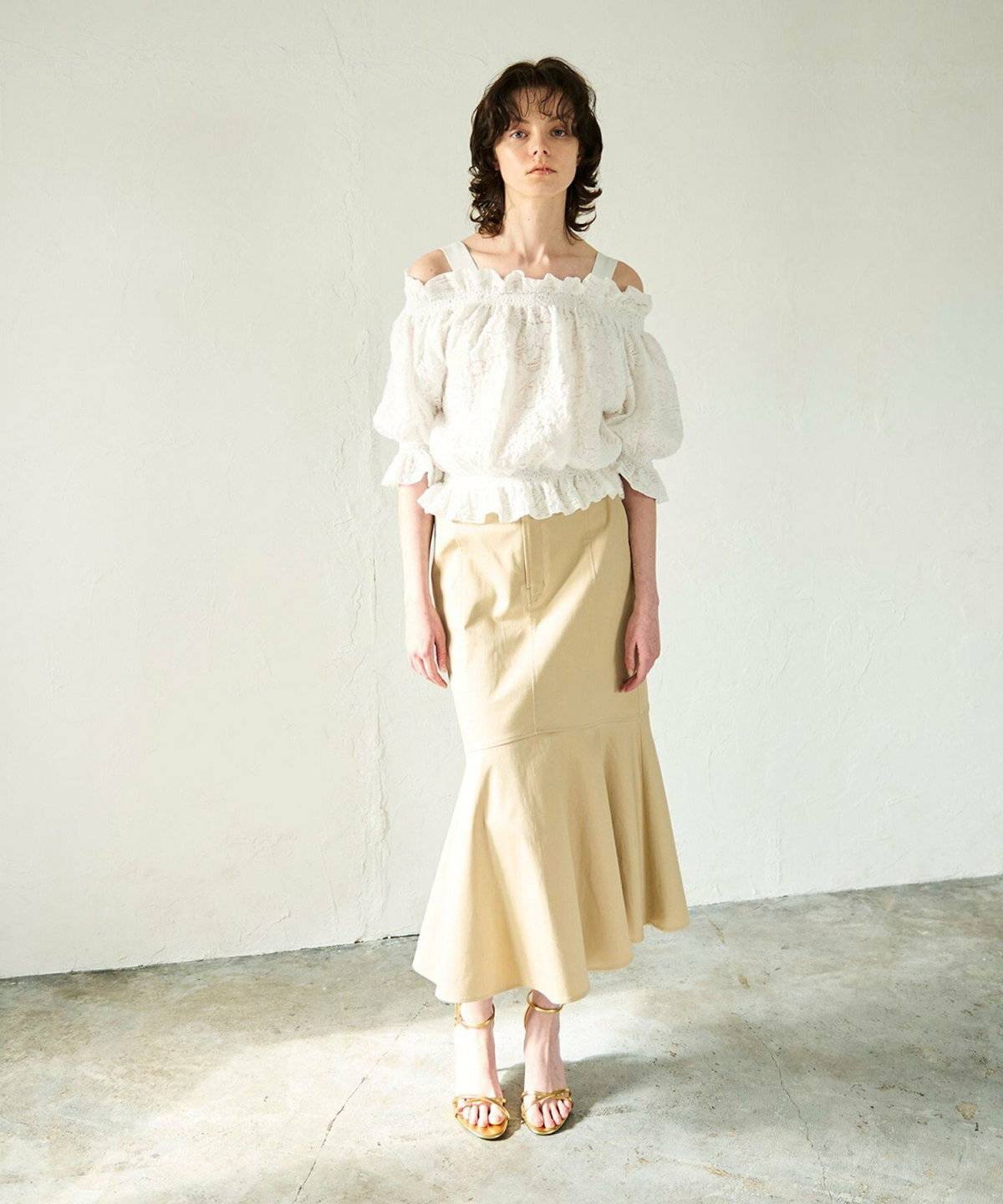 ホワイトのブラウスにベージュのスカートを合わせた女性