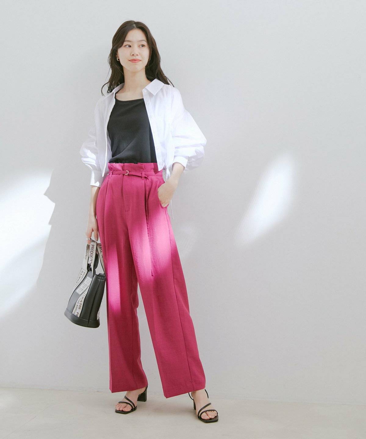 黒ニットにピンクのパンツを合わせた女性