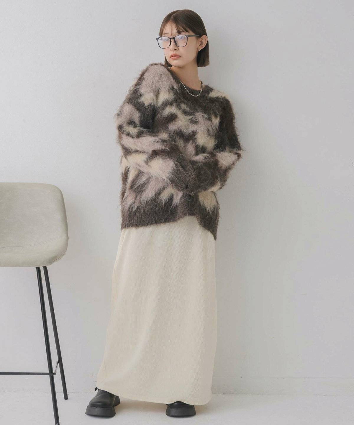ブラウンのニットに白スカートを合わせた女性