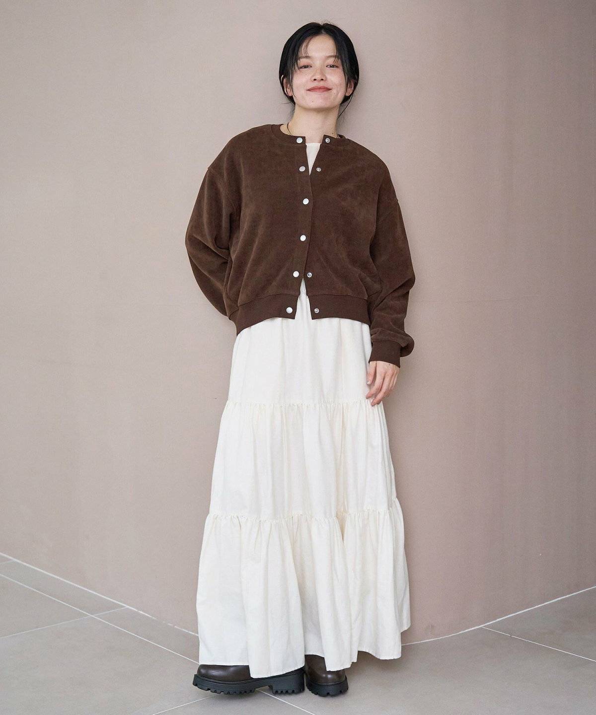 白ワンピースにブラウンのカーディガンを羽織った女性