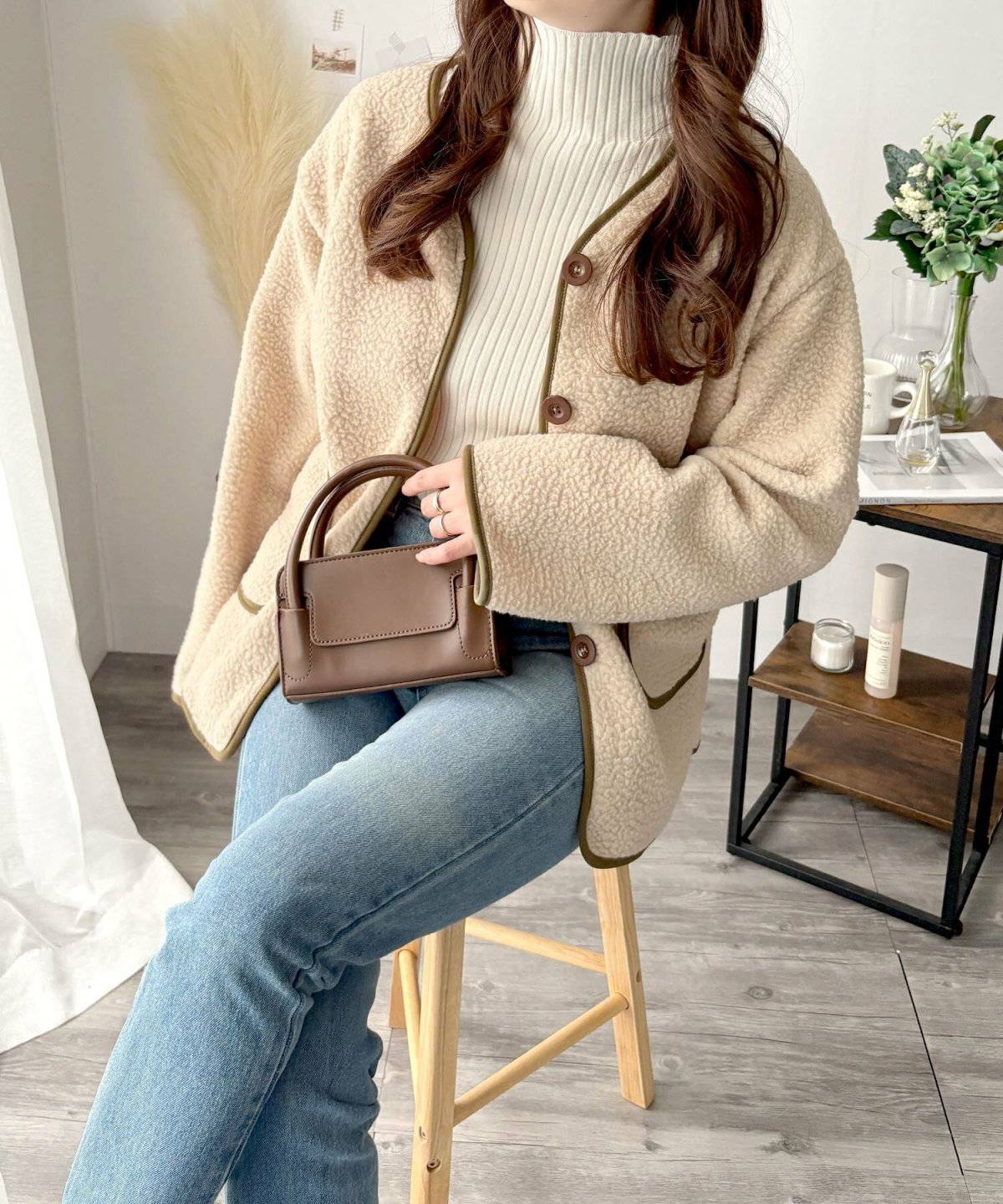 ニットにデニムパンツを合わせてベージュのコートを羽織った女性