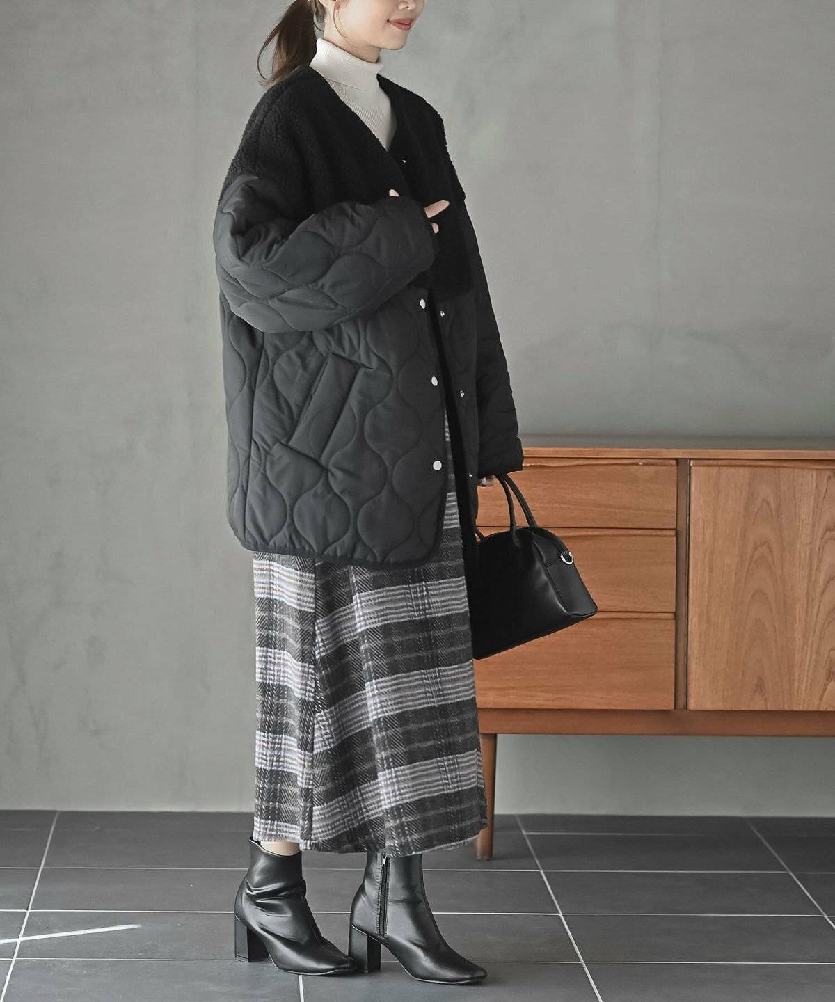 ブラウンのキルティングコートにスカートを合わせた女性