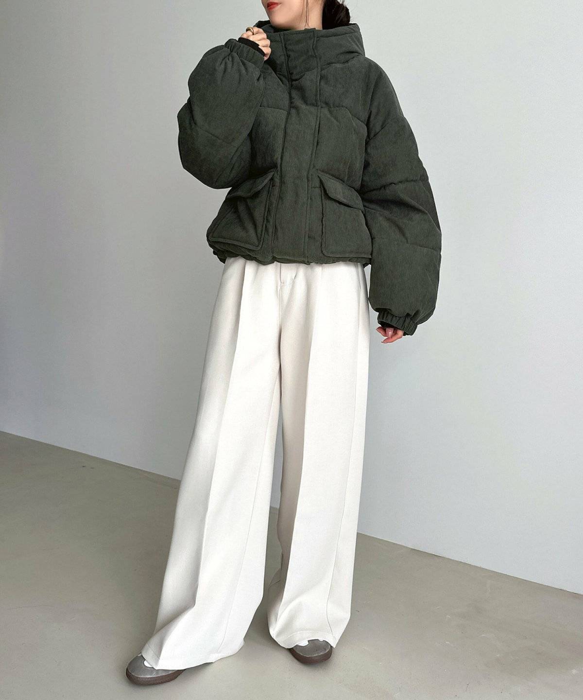 グレーのダウンに白パンツを合わせた女性