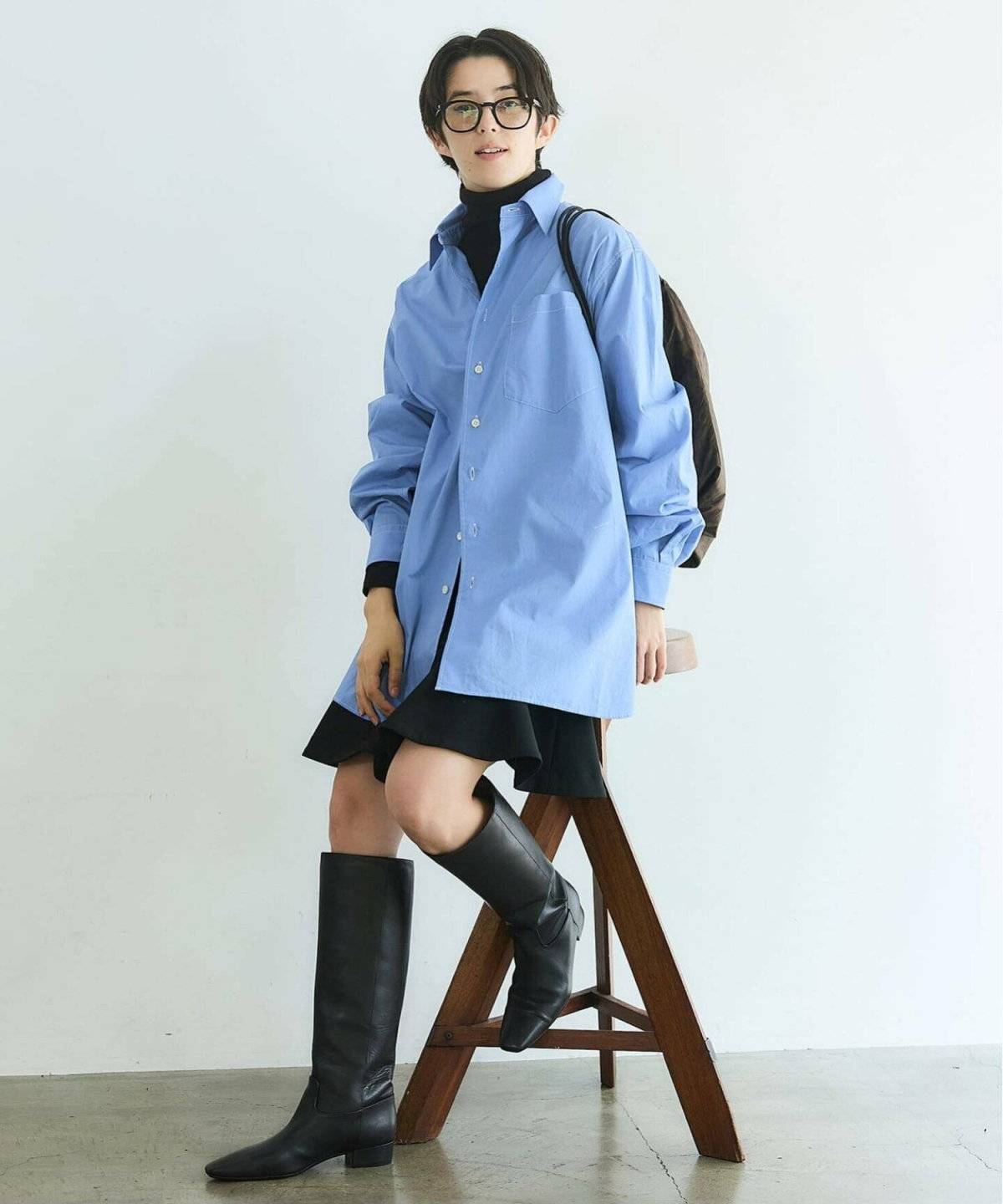 ブルーのシャツに黒パンツを合わせた女性