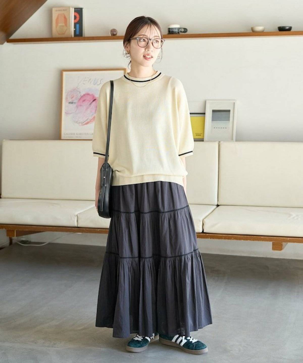 ベージュのトップスに黒スカートを合わせた女性