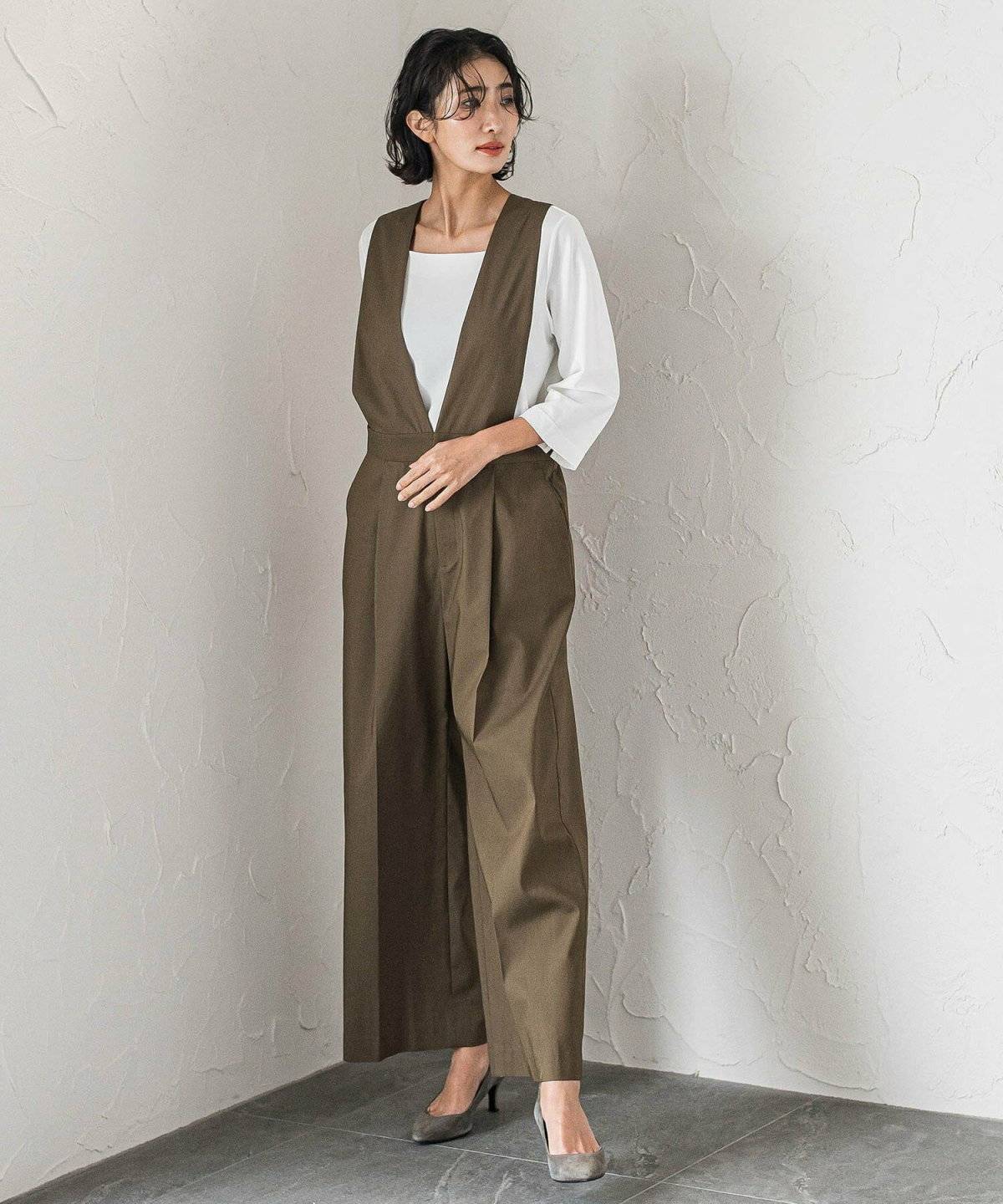 白トップスにグリーンのオールインワンを着た女性