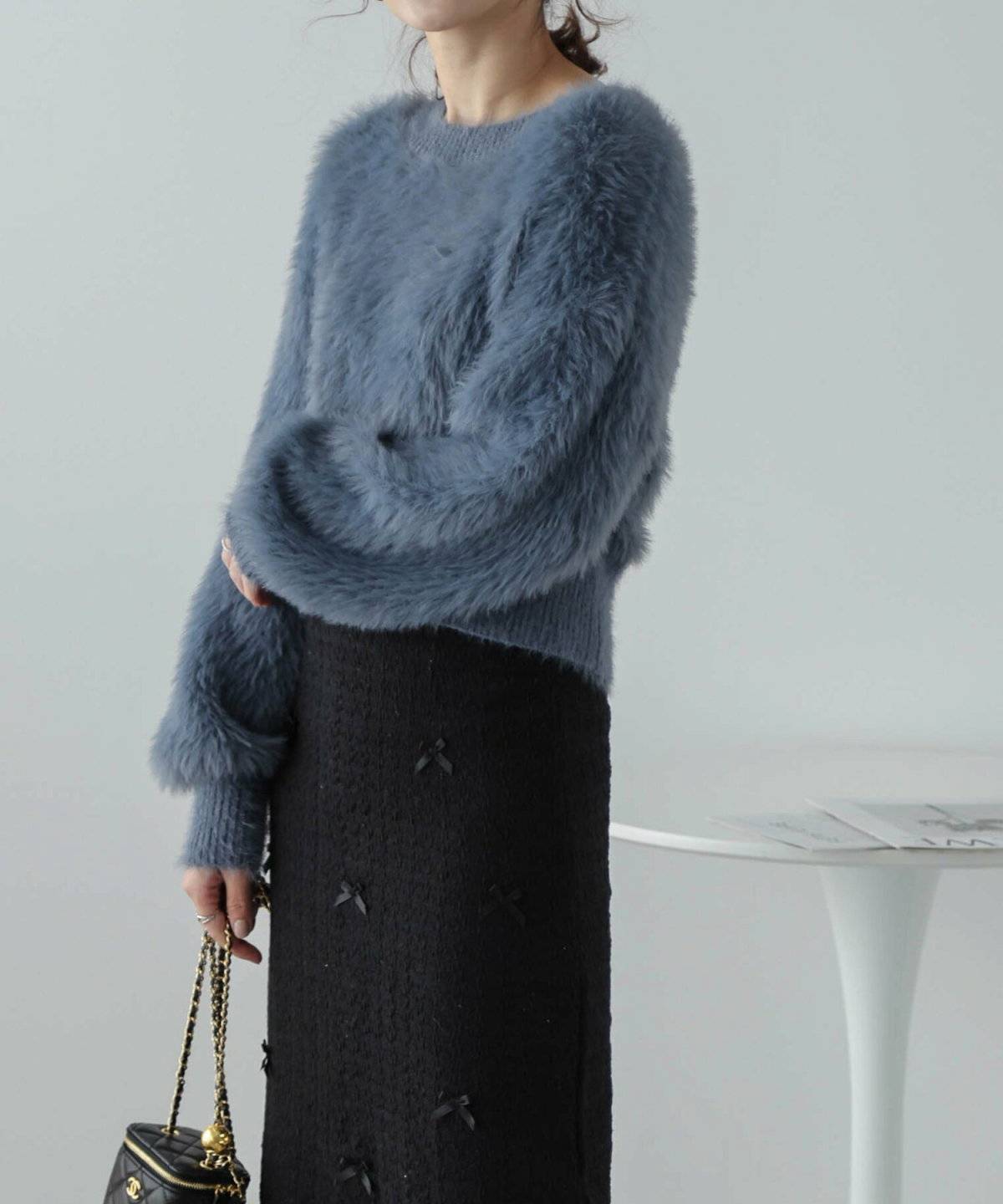 ブルーのニットに黒スカートを合わせた女性