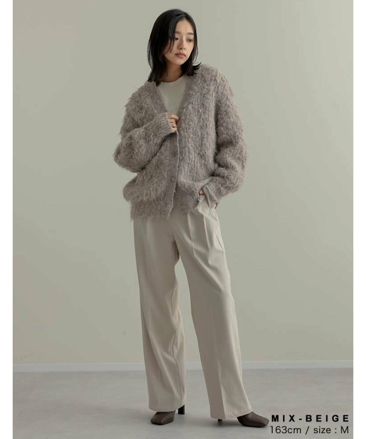 グレーのカーディガンにパンツを合わせた女性