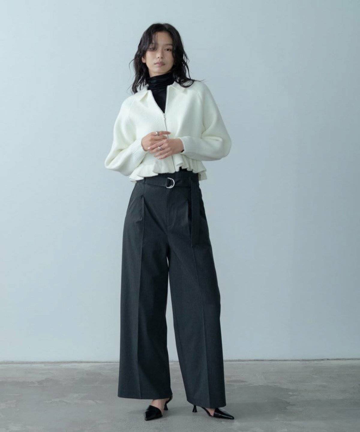 白ニットにグレーのパンツを合わせた女性