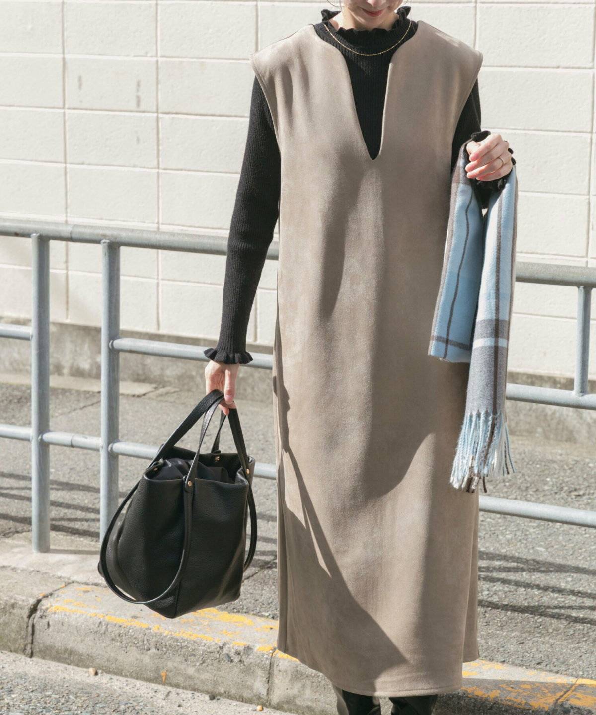 黒トップスにブラウンのワンピースを合わせた女性