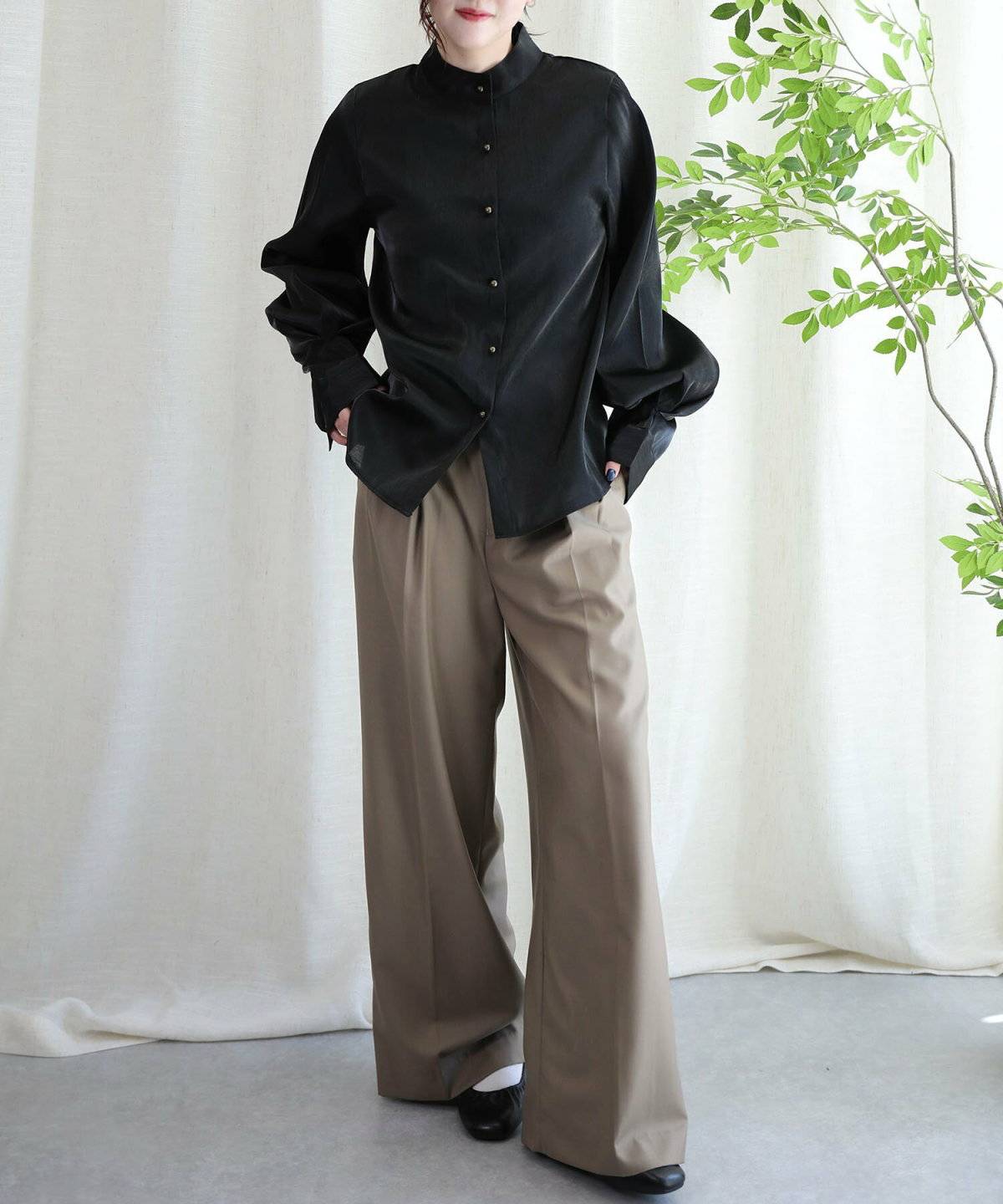 黒ブラウスにグリーンのパンツを合わせた女性