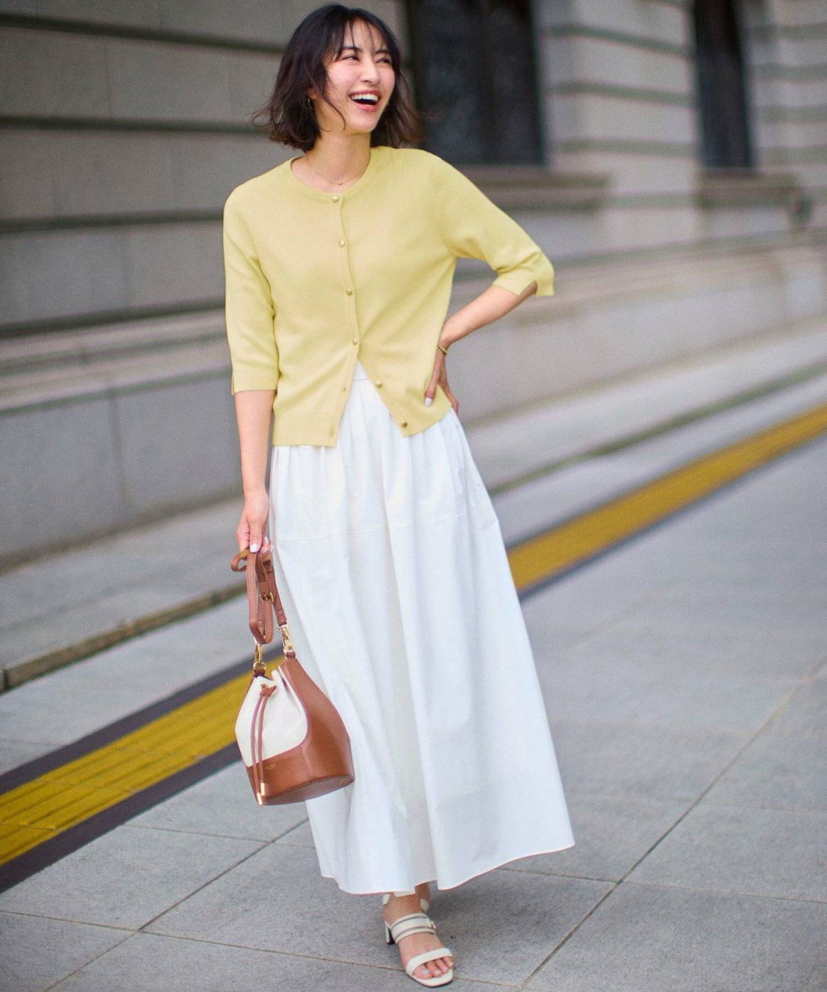 イエローのトップスにベージュのスカートを合わせた女性