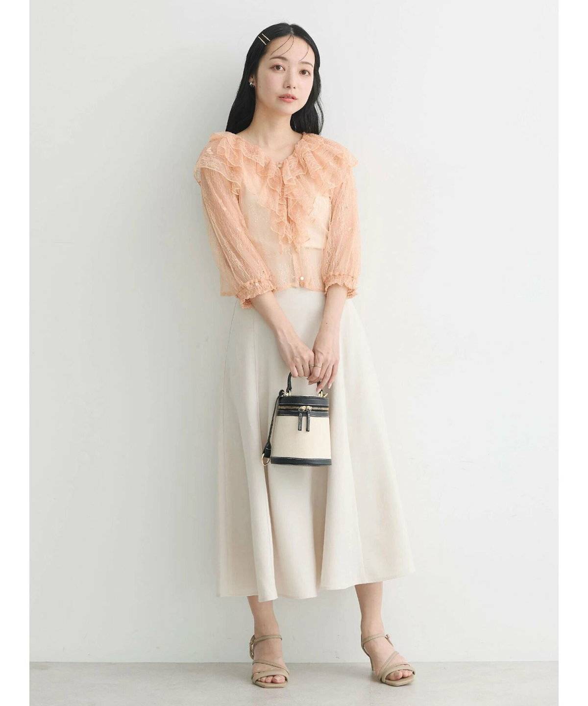 オレンジのブラウスにホワイトのスカートを合わせた女性